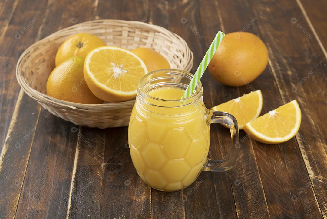 Suco de laranja com laranja fatiada sobre uma mesa de madeira.