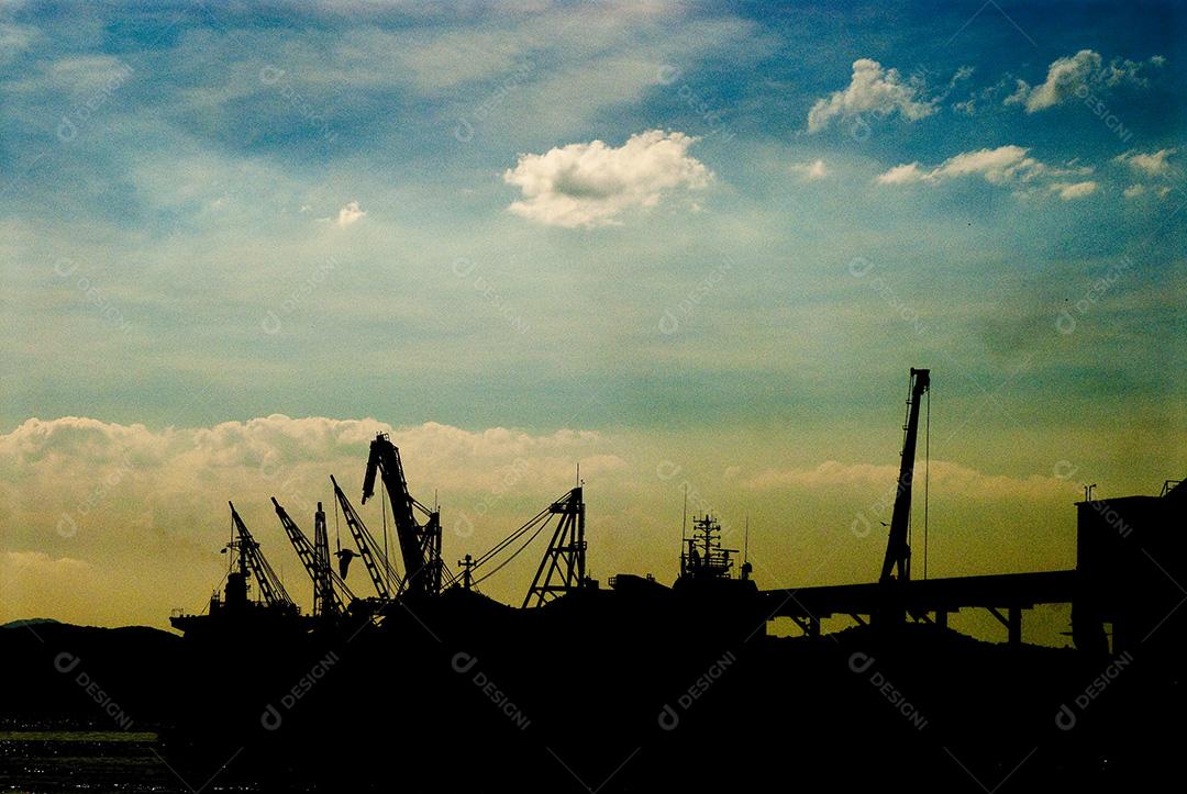 Silhueta de grandes guindastes ao pôr do sol