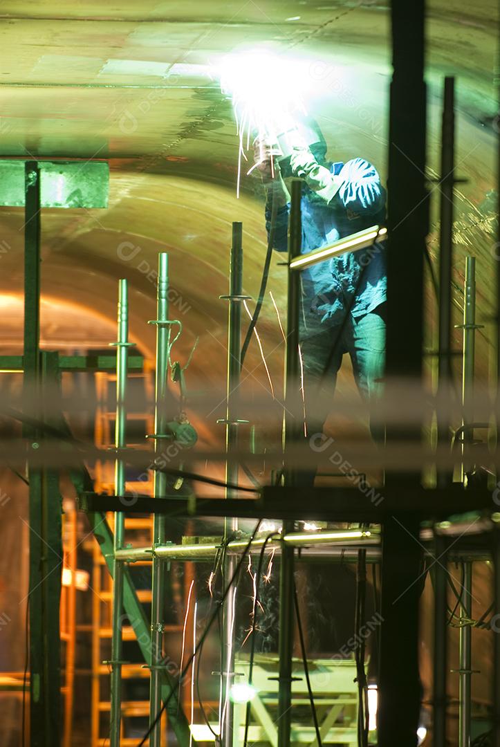 Homem trabalhando, soldando ferro, equipado. Trabalho