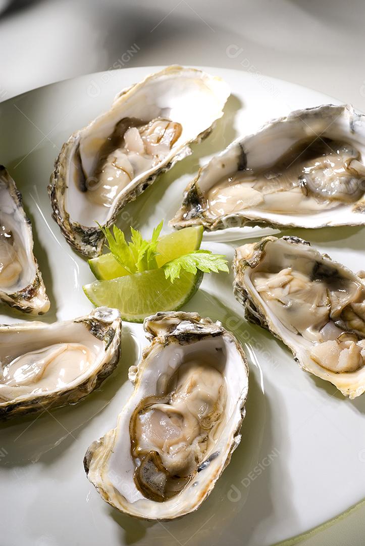 Comida típica. Ostra do pacífico com limão em prato branco