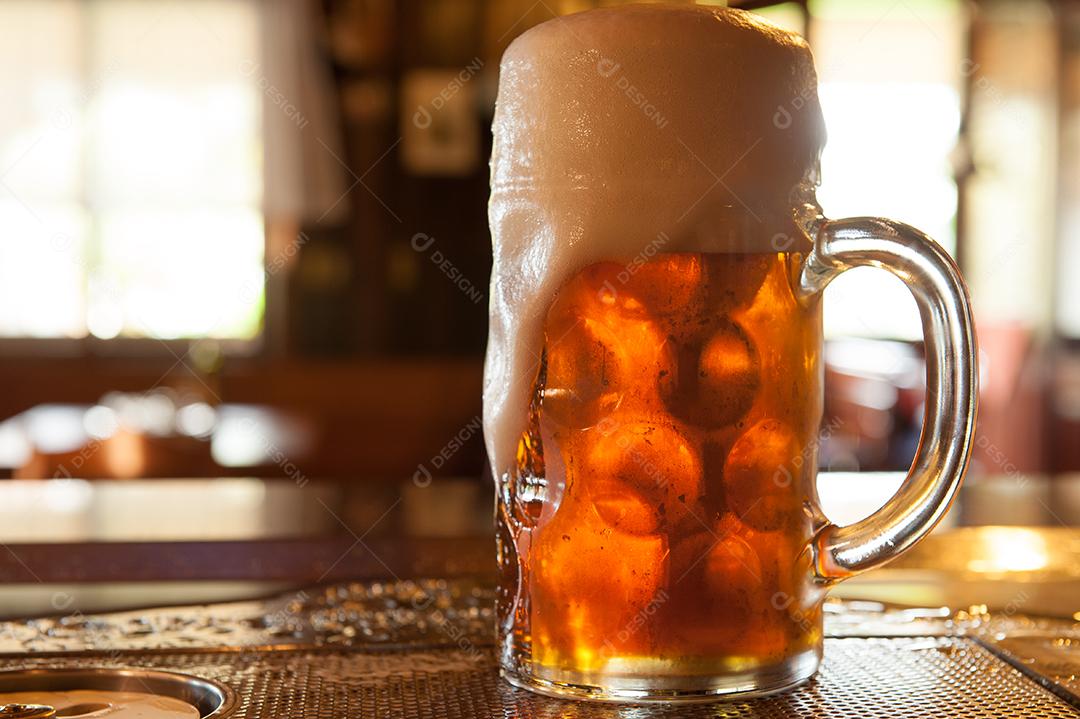 cerveja servida em caneca transparente com espuma em um bar