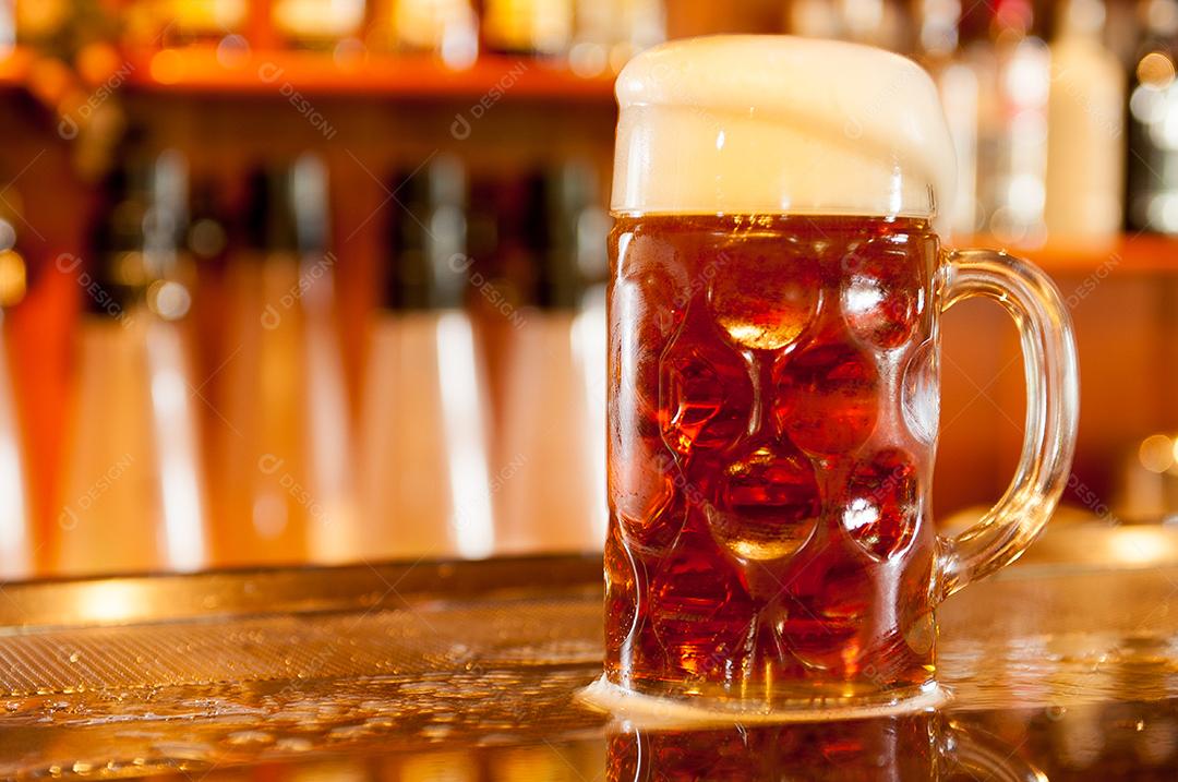 cerveja servida em caneca transparente com espuma em um bar