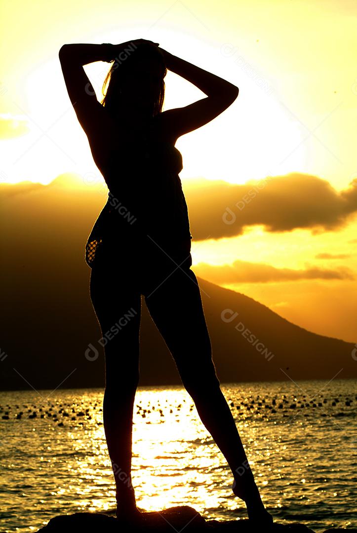 Mulher com braços para cima relaxando sobre fundo de paisagem natural.