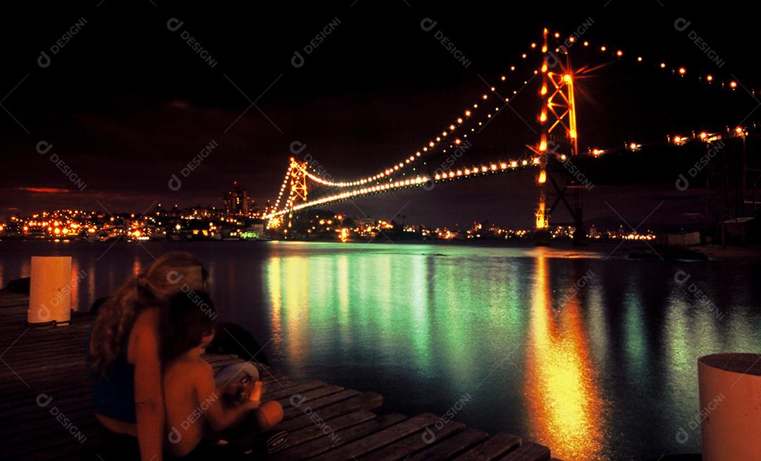 Mulher e garoto olhando ponte grande iluminada. Paisagem linda