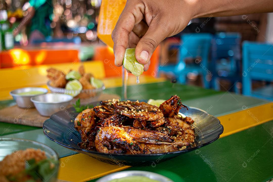 Camarão seco  sobre prato com limões e coentro.