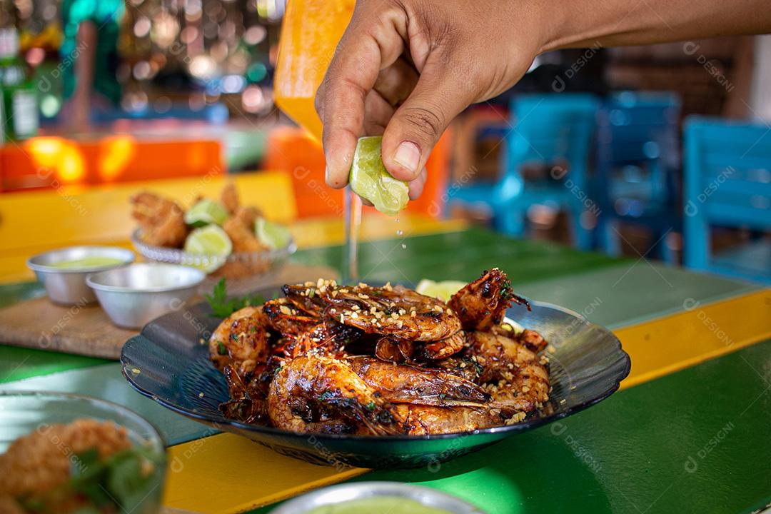 Camarão seco  sobre prato com limões e coentro.