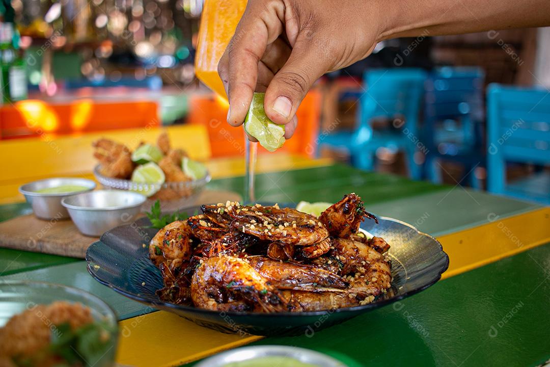 Camarão seco  sobre prato com limões e coentro.