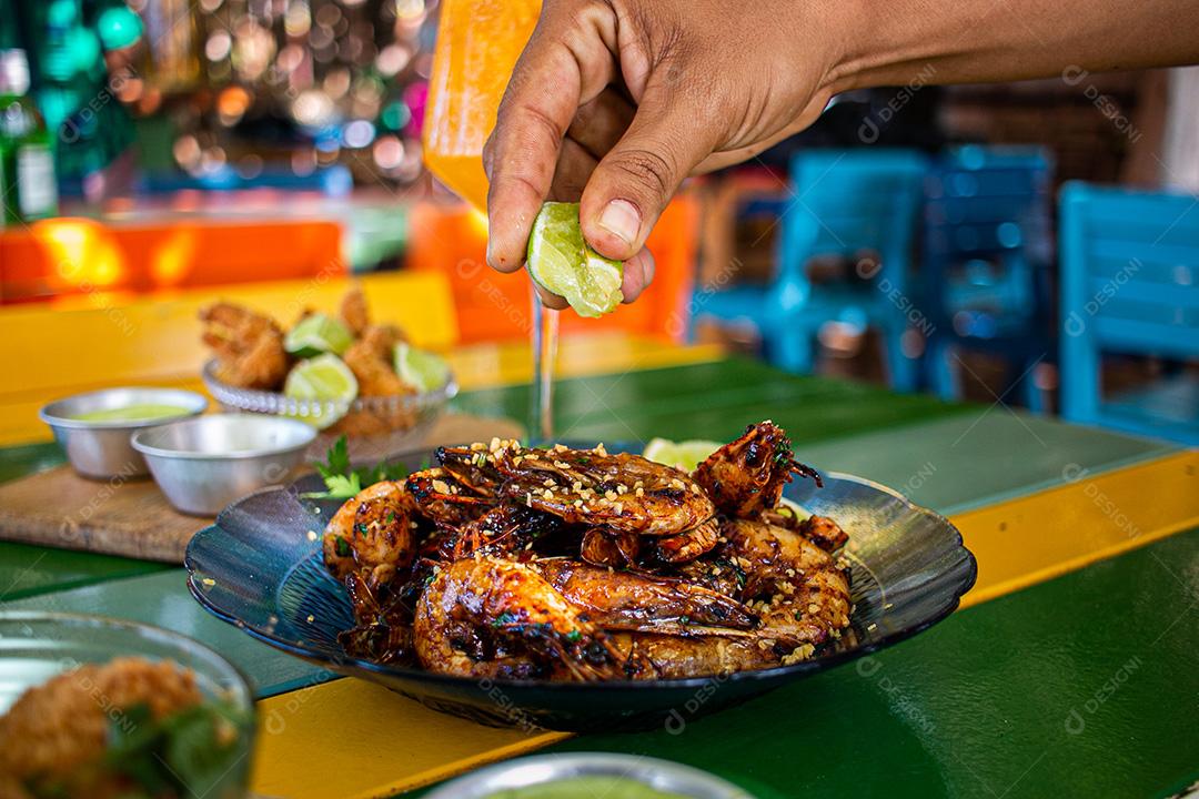 Camarão seco  sobre prato com limões e coentro.