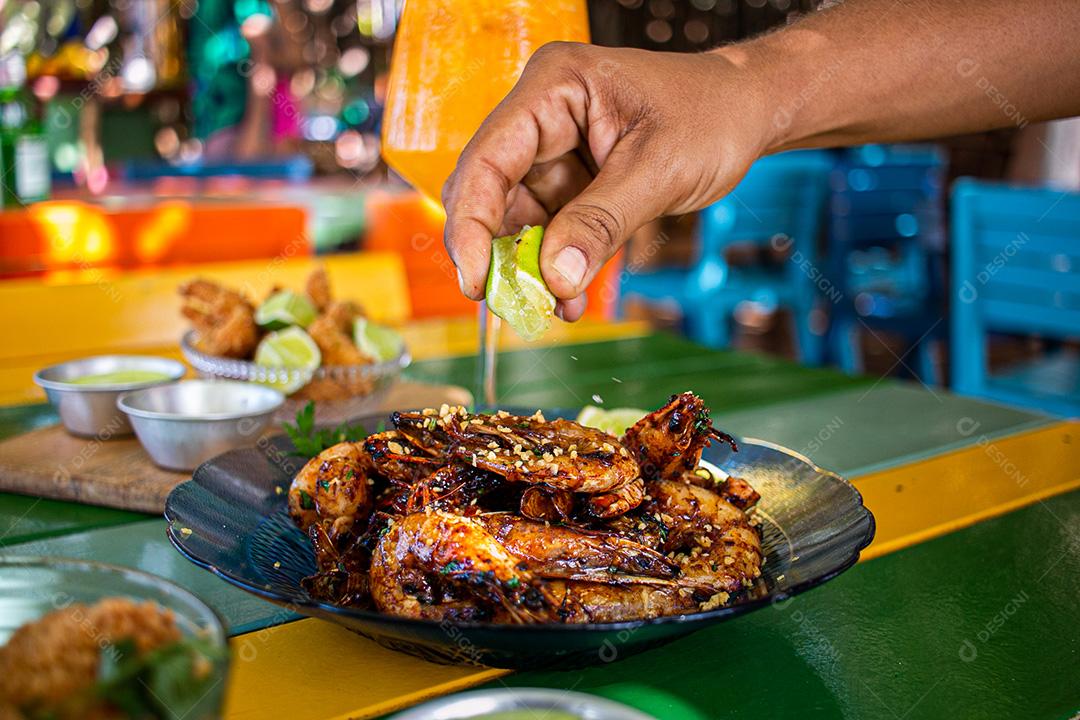 Camarão seco  sobre prato com limões e coentro.