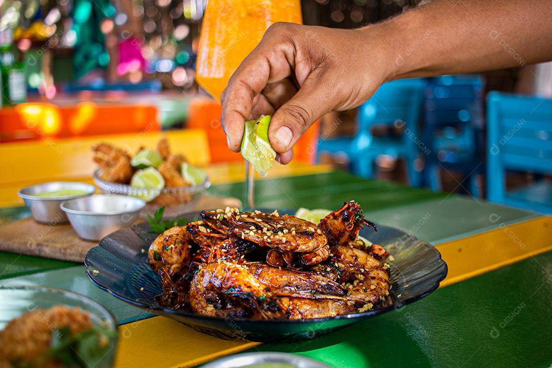 Camarão seco  sobre prato com limões e coentro.