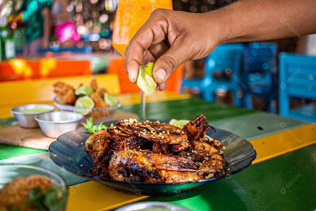 Camarão seco  sobre prato com limões e coentro.