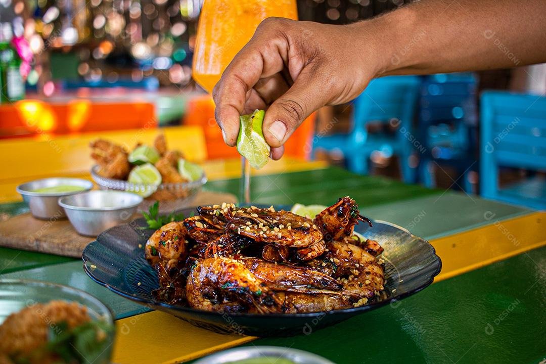 Camarão seco  sobre prato com limões e coentro.