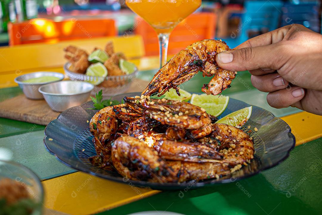 Camarão seco  sobre prato com limões e coentro.