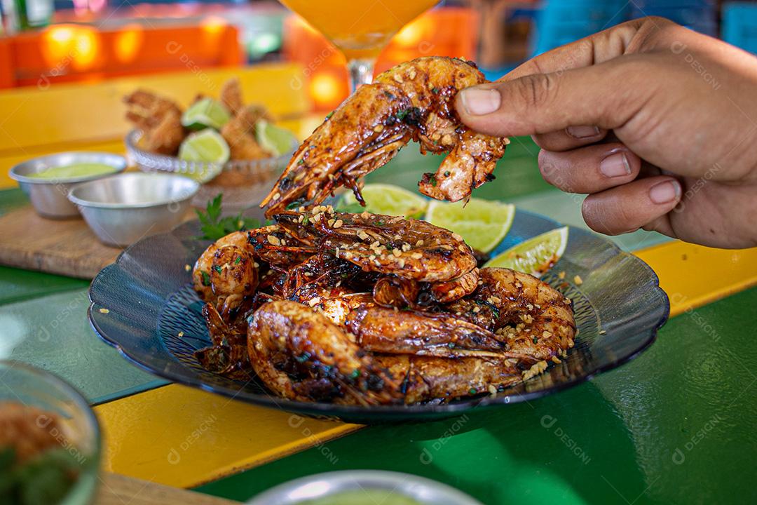 Camarão seco  sobre prato com limões e coentro.