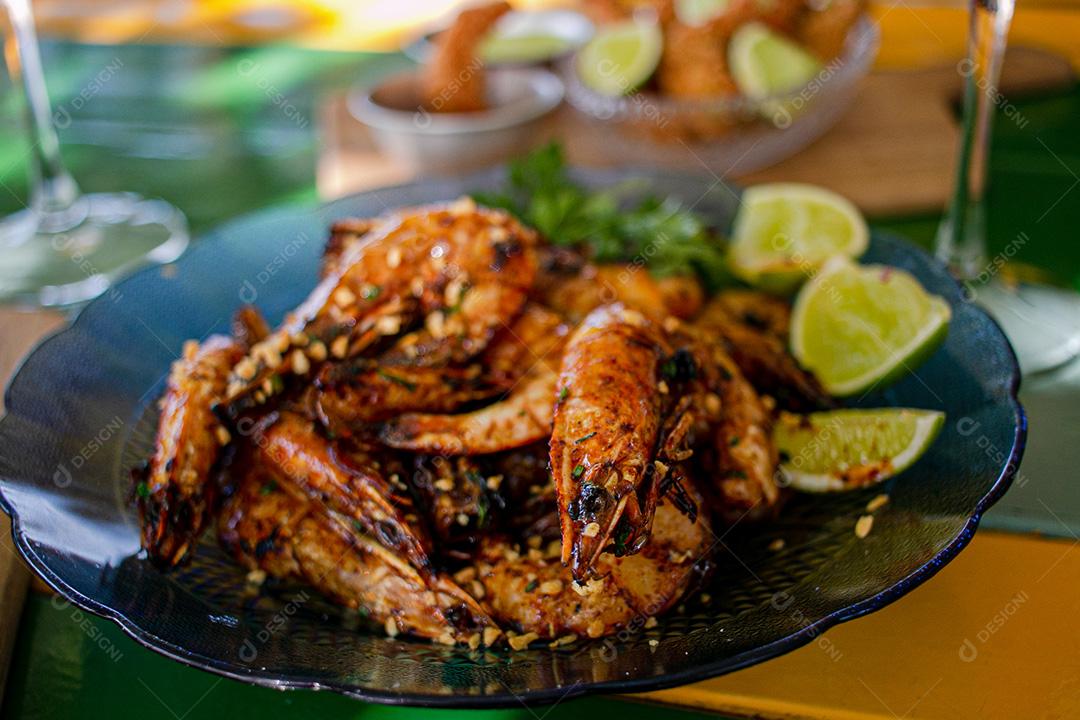 Camarão seco  sobre prato com limões e coentro.