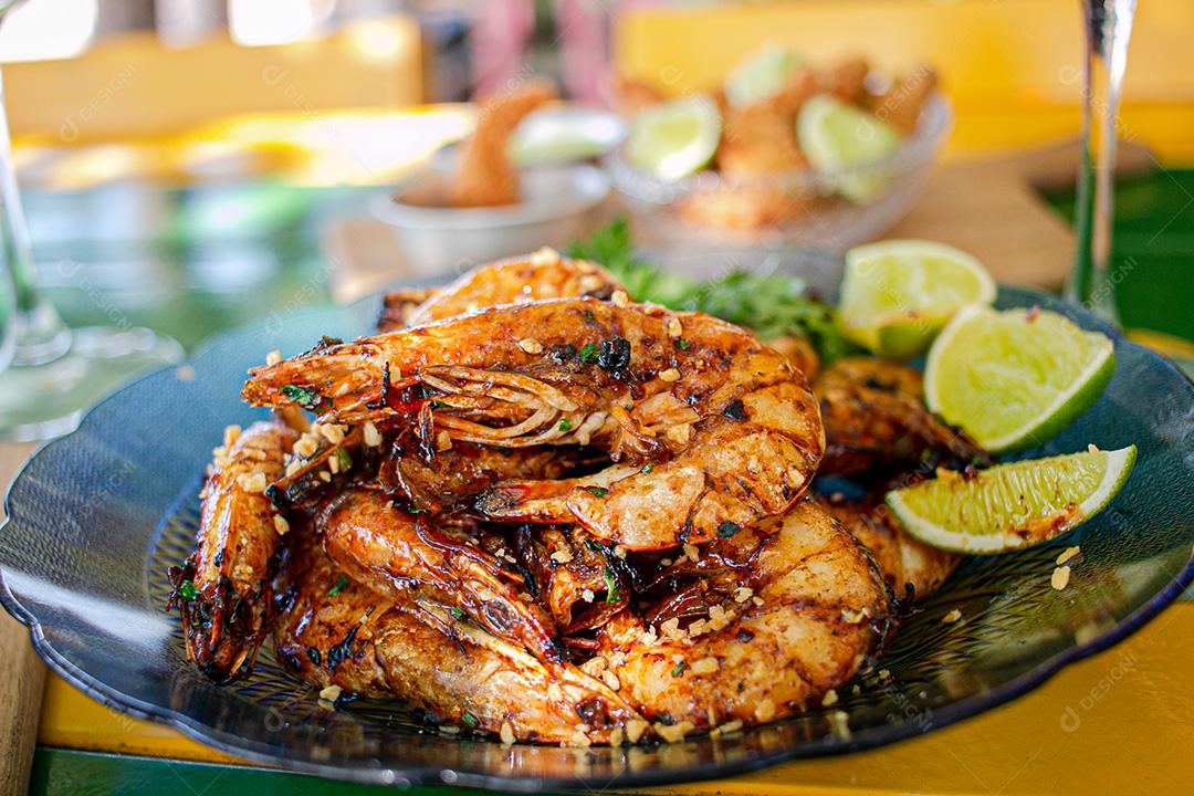 Camarão seco  sobre prato com limões e coentro.