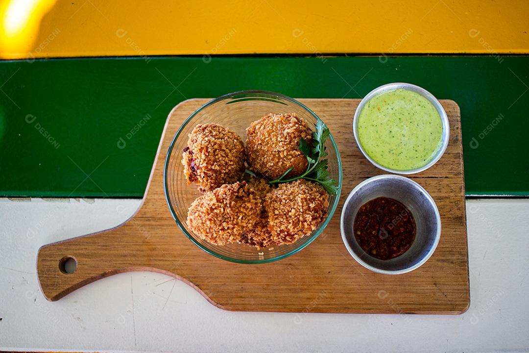 Salgadinho com molho de pimenta, molho verde temperado.