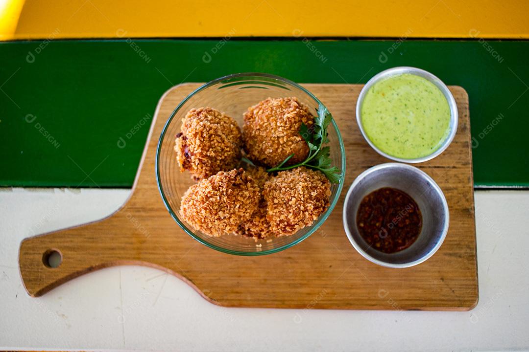 Salgadinho com molho de pimenta, molho verde temperado.