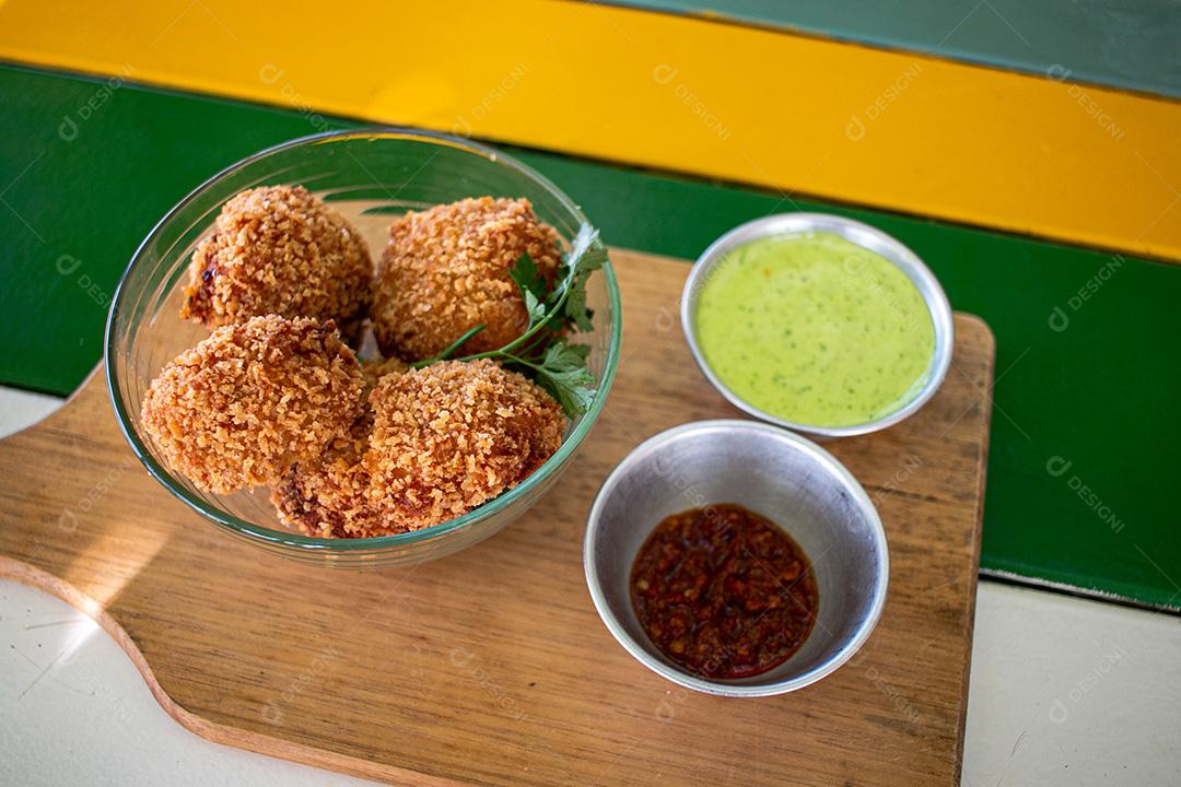 Salgadinho com molho de pimenta, molho verde temperado.