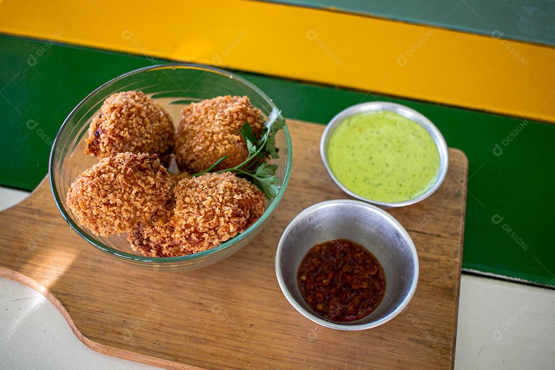 Salgadinho com molho de pimenta, molho verde temperado.
