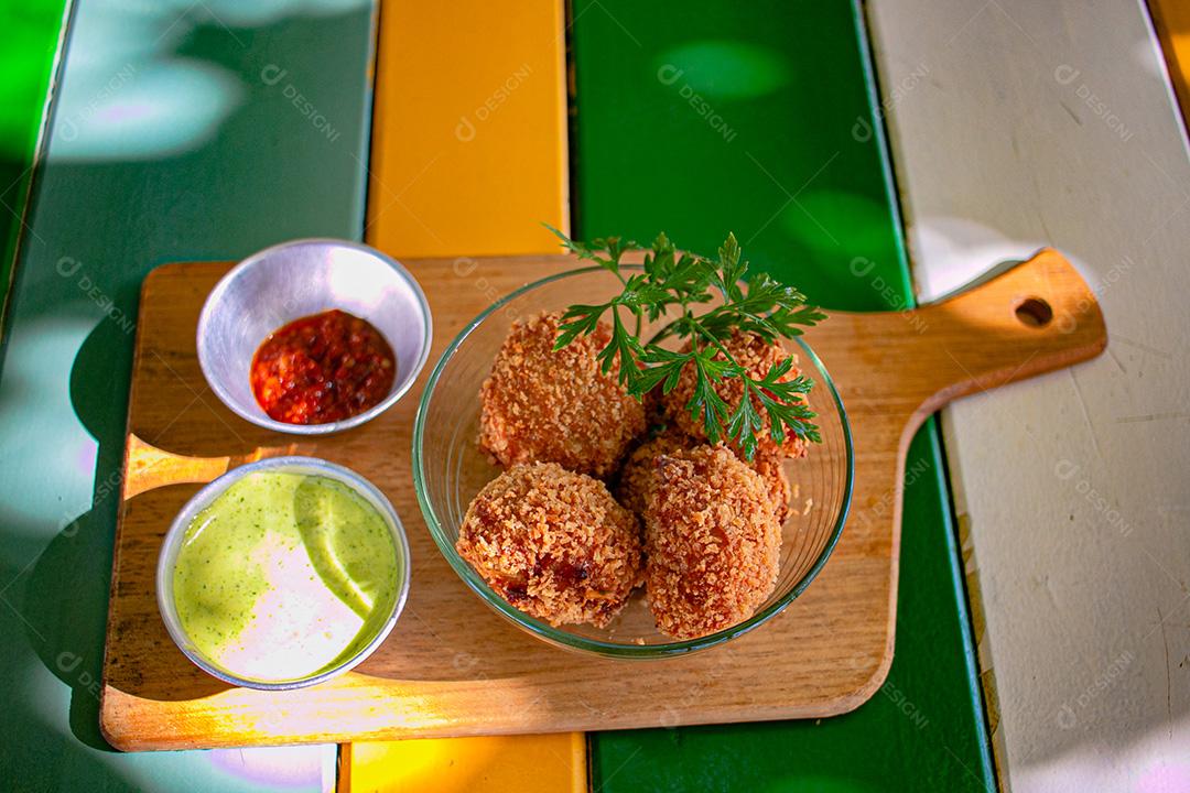 Salgadinho com molho de pimenta, molho verde temperado.