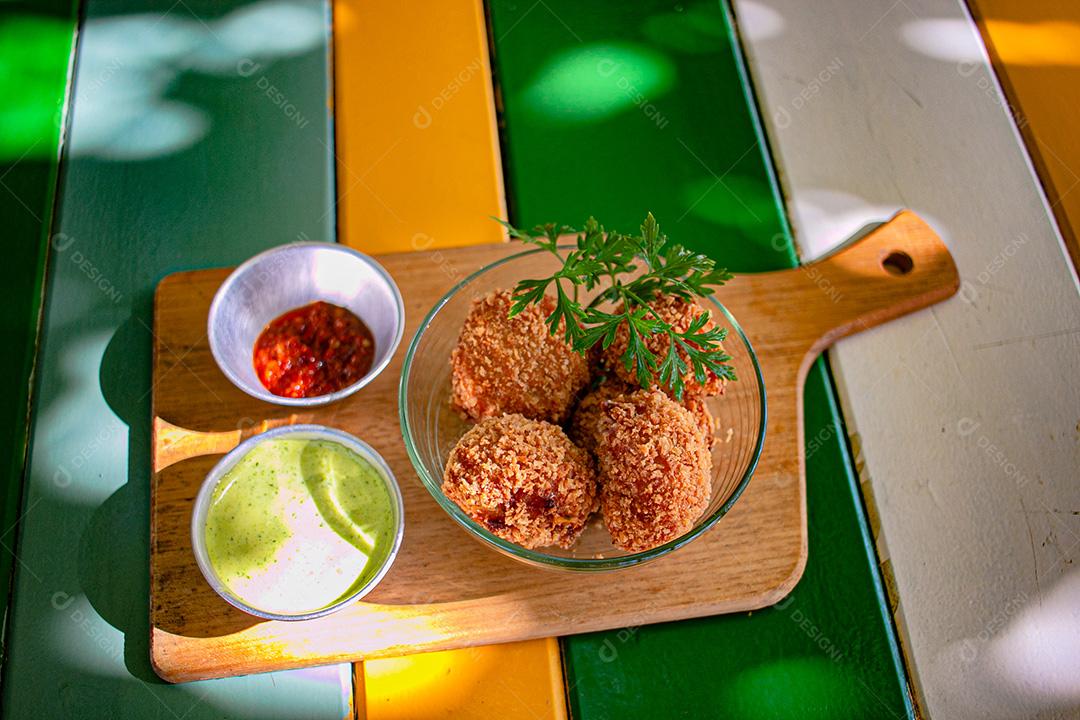 Salgadinho com molho de pimenta, molho verde temperado.