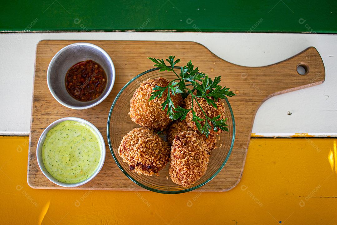 Salgadinho com molho de pimenta, molho verde temperado.
