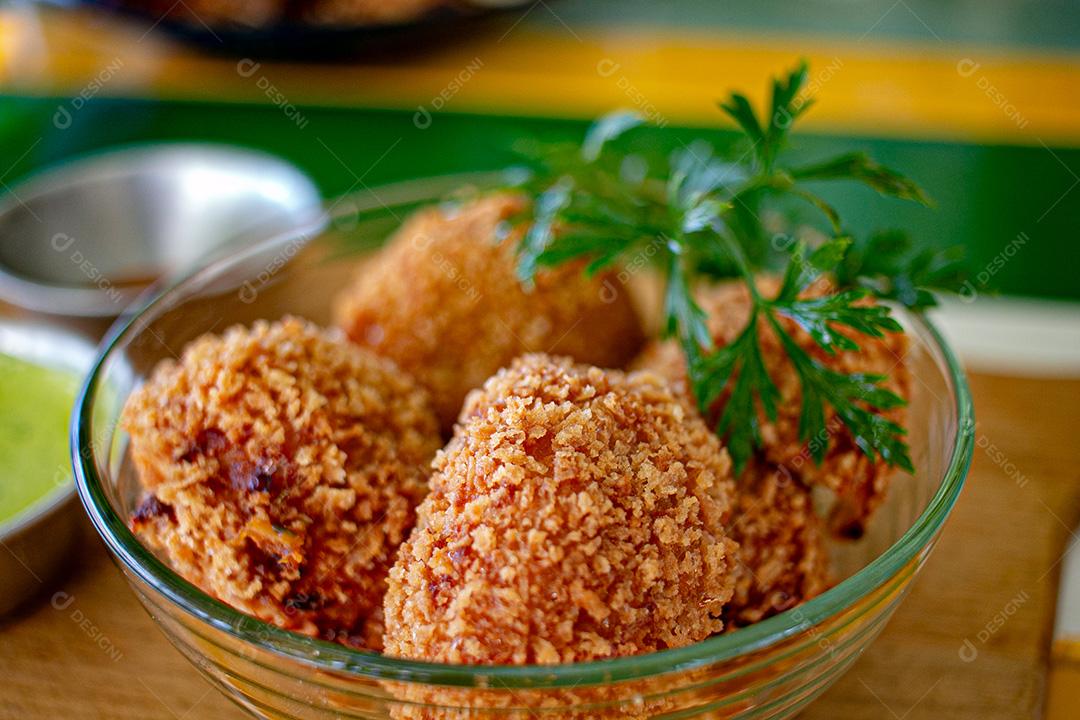 Salgadinho com molho de pimenta, molho verde temperado.