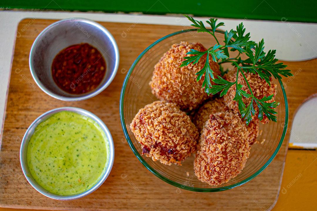 Salgadinho com molho de pimenta, molho verde temperado.