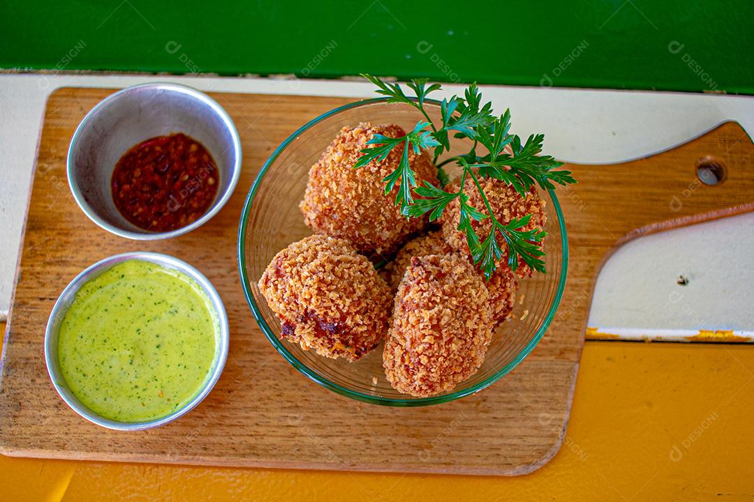 Salgadinho com molho de pimenta, molho verde temperado.