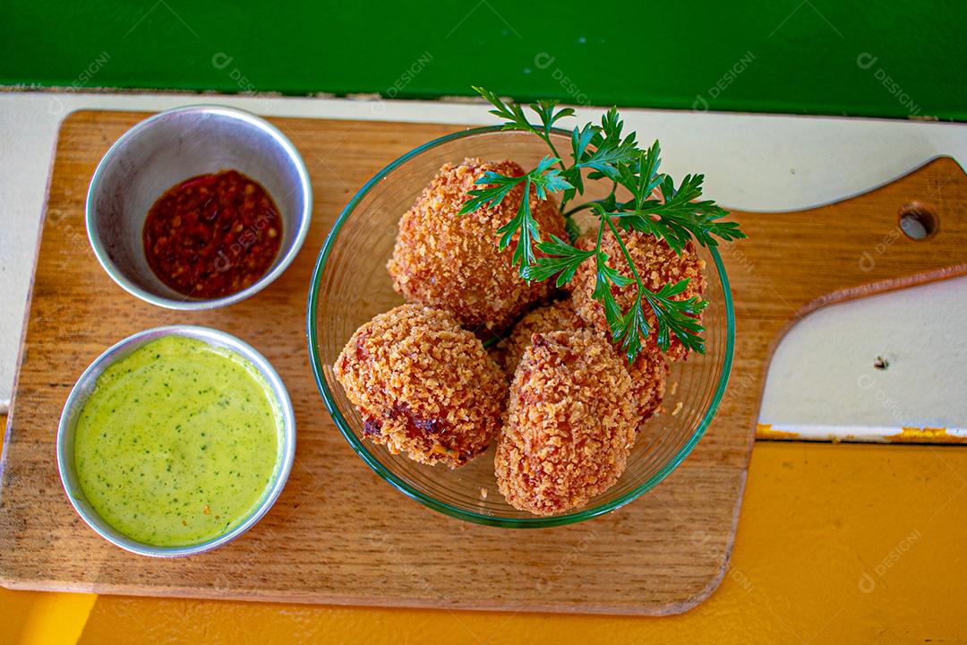 Salgadinho com molho de pimenta, molho verde temperado.