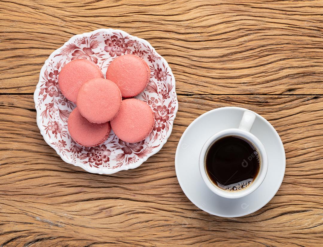 Macarons de amora em um prato com café sobre mesa de madeira
