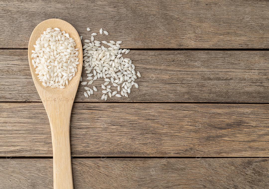 Arroz de risoto de carnaroli cru em uma colher sobre mesa de madeira