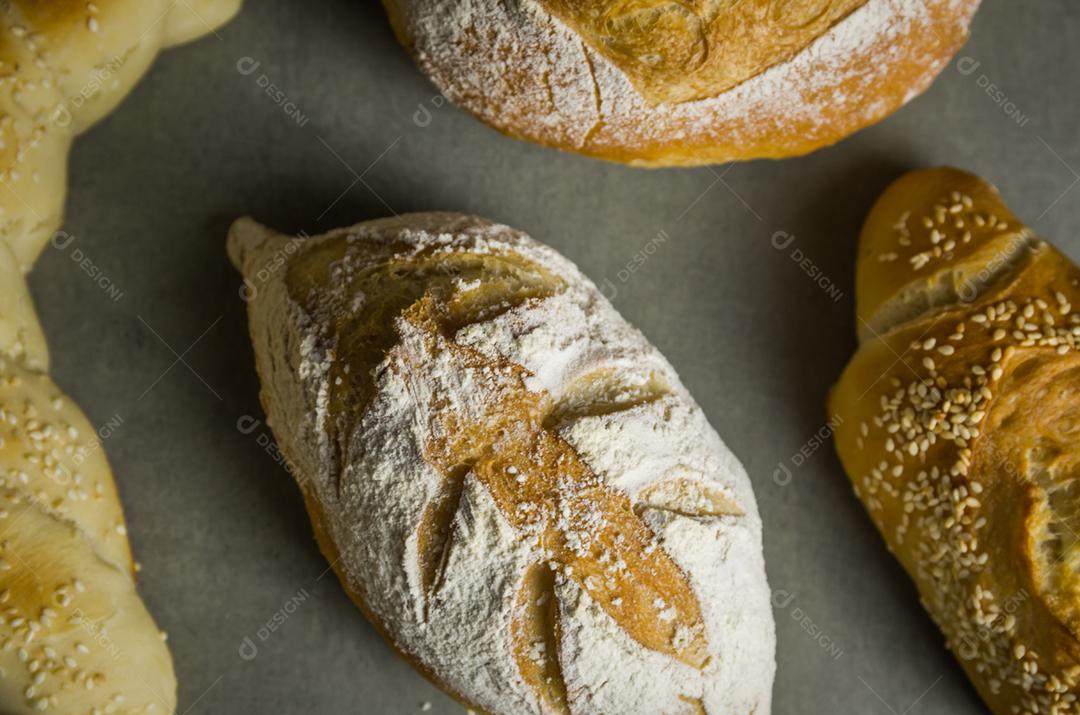 Belo pão de fermento em fundo cinza com flor de trigo seca.