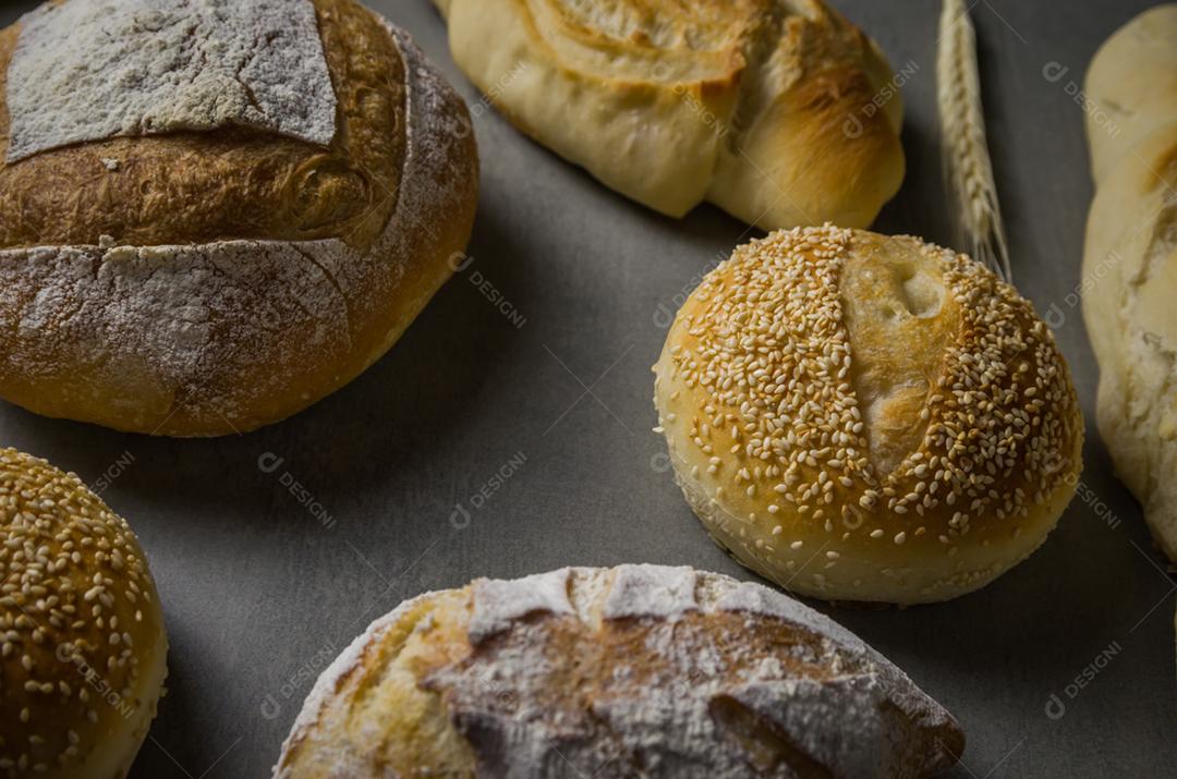 Belo pão de fermento em fundo cinza com flor de trigo seca.