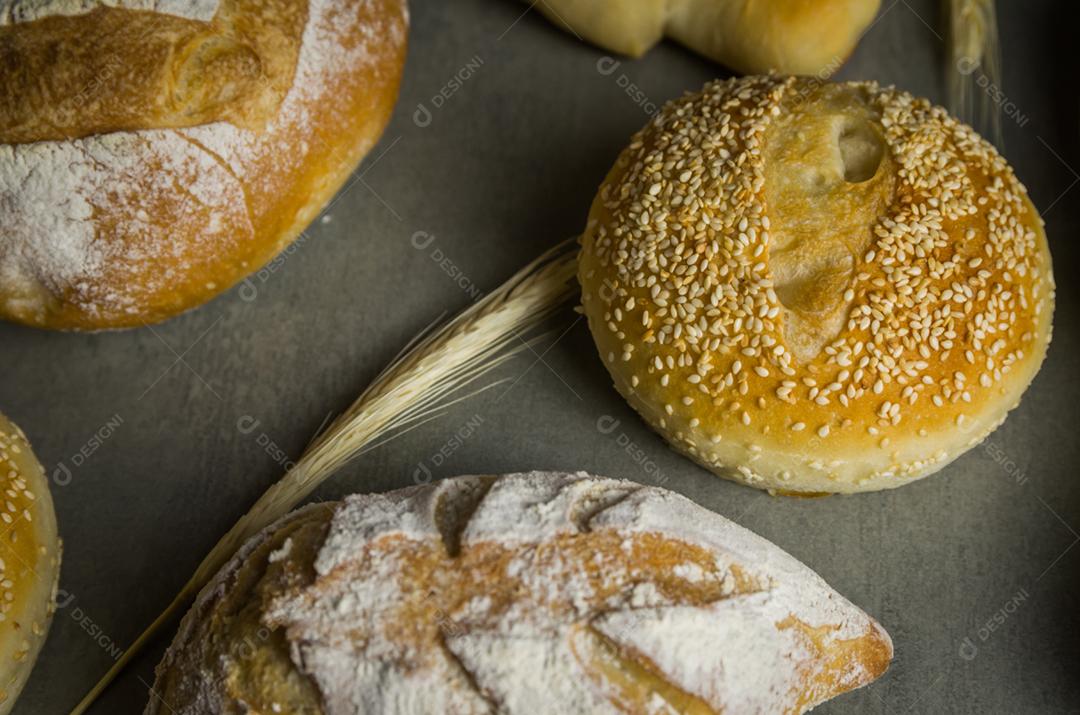 Belo pão de fermento em fundo cinza com flor de trigo seca.
