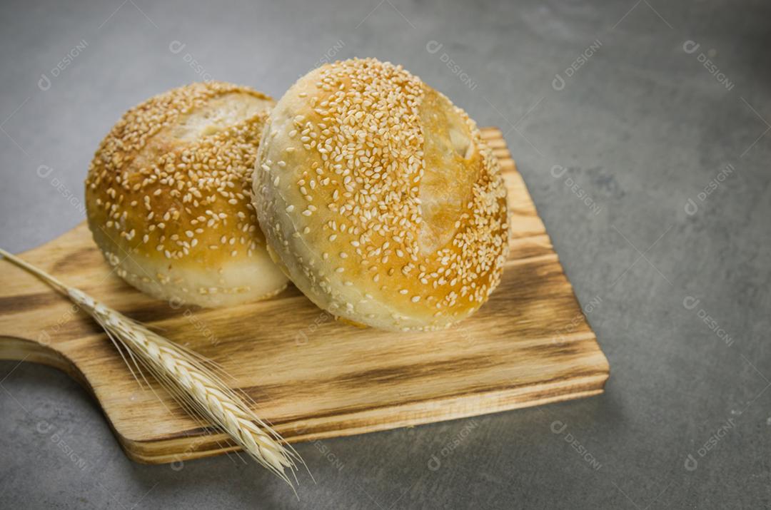 Belo pão de fermento em fundo cinza com flor de trigo seca.