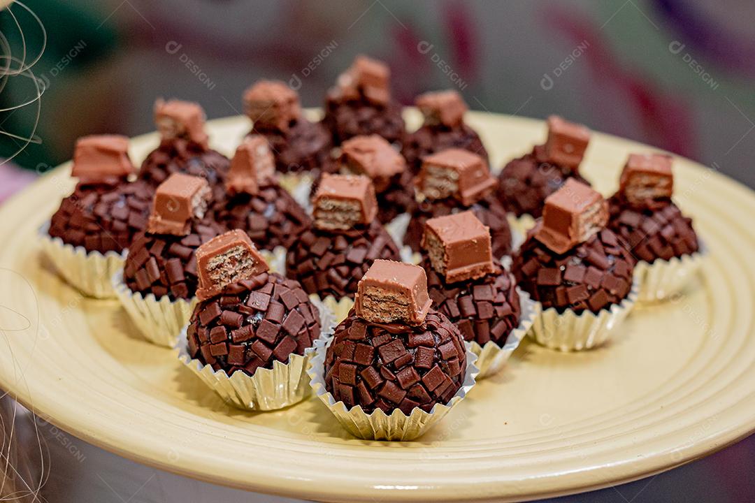 Brigadeiros de chocolate confeitados sobre prato amarelo