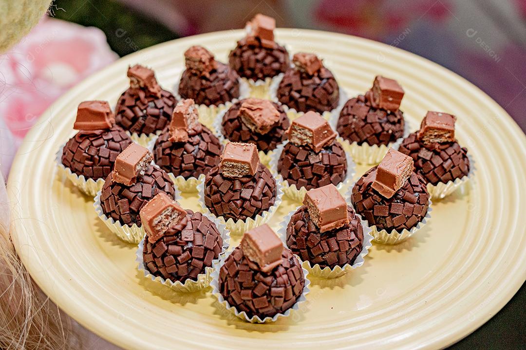 Brigadeiros de chocolate confeitados sobre prato amarelo
