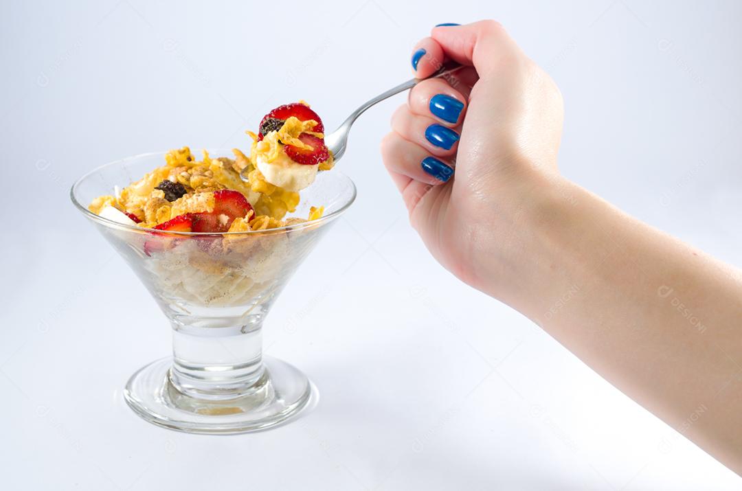 Mão de mulher pegando granola com colher