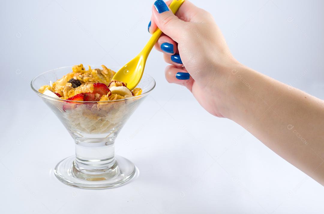 Mão de mulher pegando granola com colher