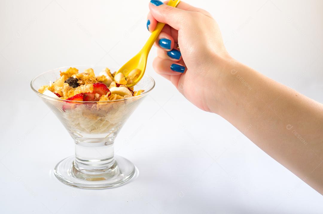 Mão de mulher pegando granola com colher