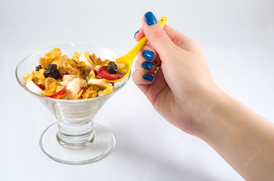 Mão de mulher pegando granola com colher