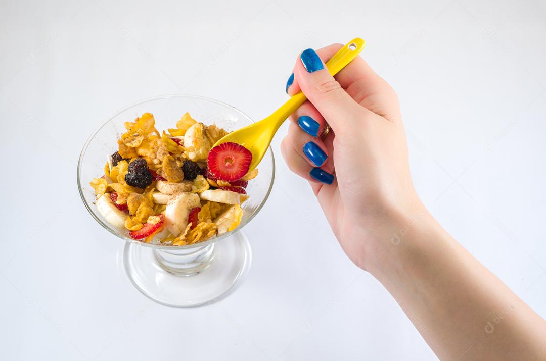 Mão de mulher pegando granola com colher