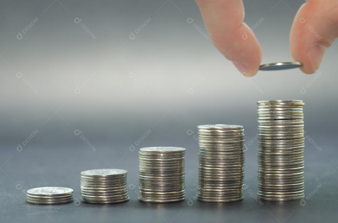 Grande conceito de poupança, economia. Mão adicionando moeda na pilha de moedas.