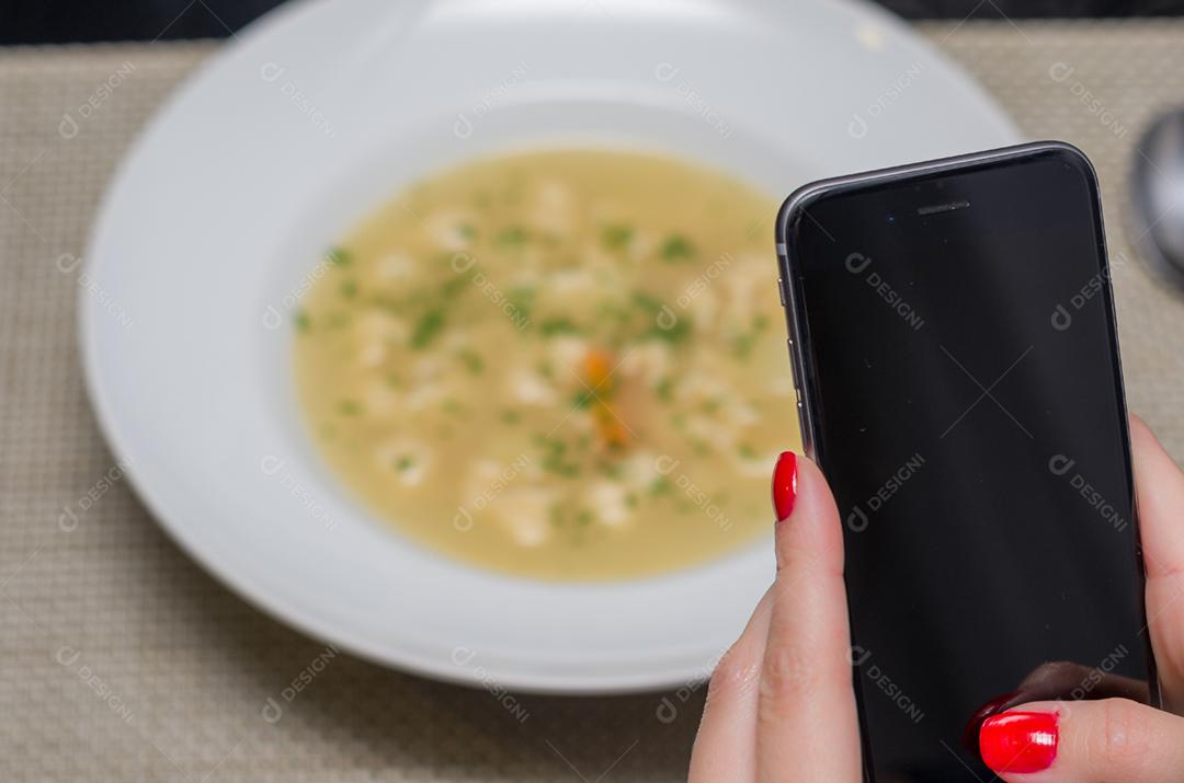 Grande conceito de mídia social, mão de mulher tirando foto de comida (sopa).