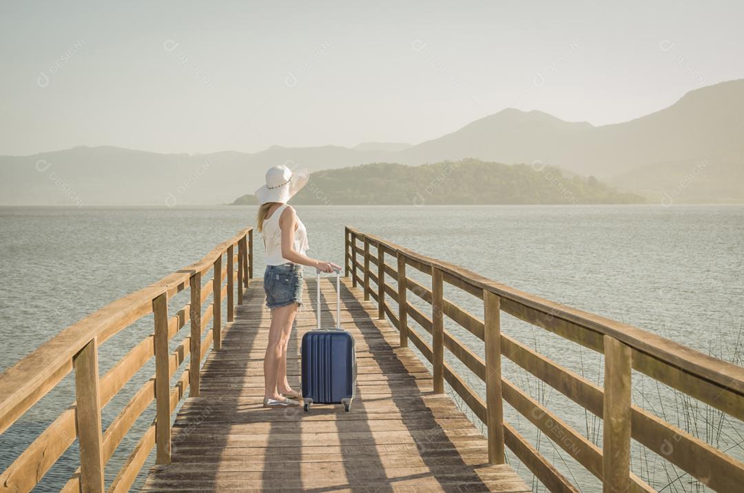 Grande conceito de férias. Jovem mulher segurando sua mala, esperando o barco no cais
