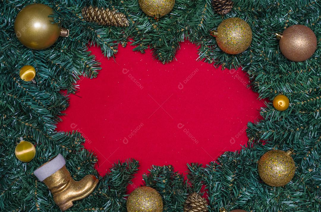 Fundo com tema natalino, folhas de pinheiro nas bordas de papel vermelho e objetos decorativos.