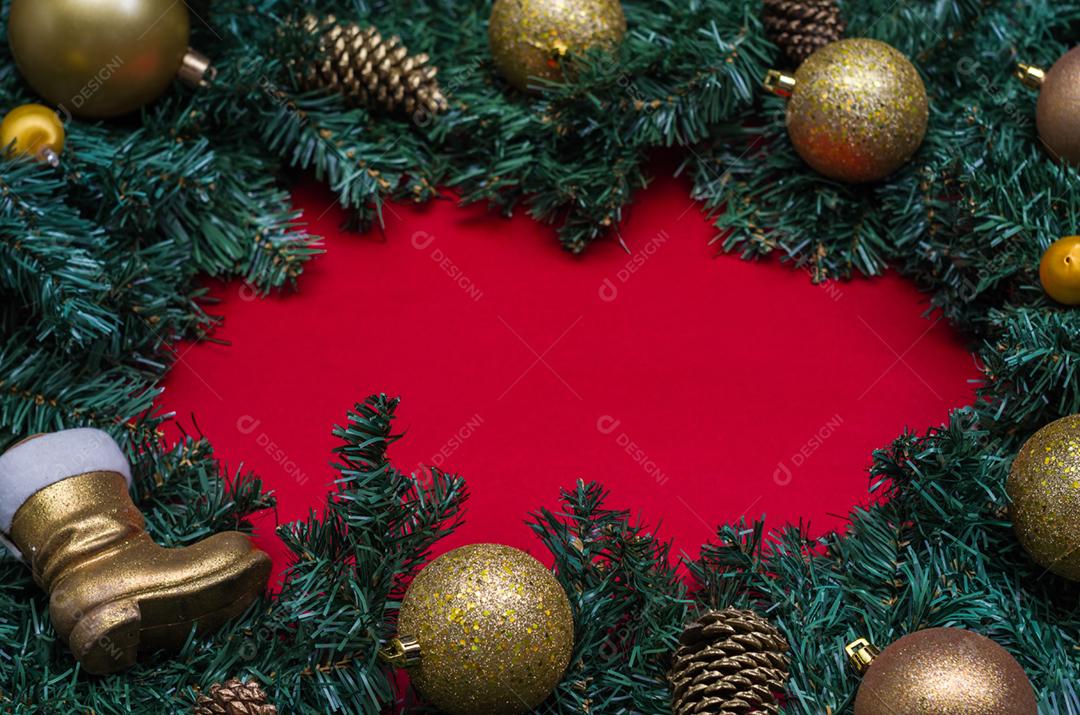 Fundo com tema natalino, folhas de pinheiro nas bordas de papel vermelho e objetos decorativos.
