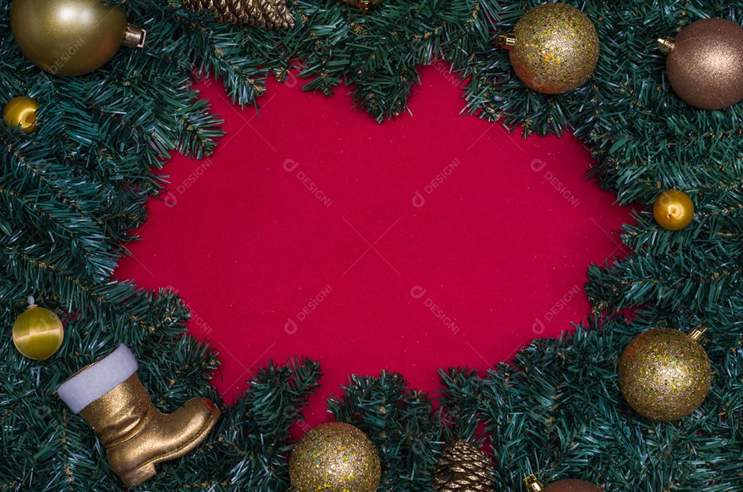Fundo com tema natalino, folhas de pinheiro nas bordas de papel vermelho e objetos decorativos.